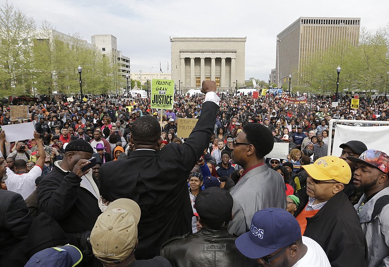 Malik Z. Shabazz, center, of Black Lawyers for Justice raises his fist as he speaks at a rally for Freddie Gray outside Baltimore City Hall on  Saturday, April 25, 2015. Gray died from spinal injuries about a week after he was arrested and transported in a police van.