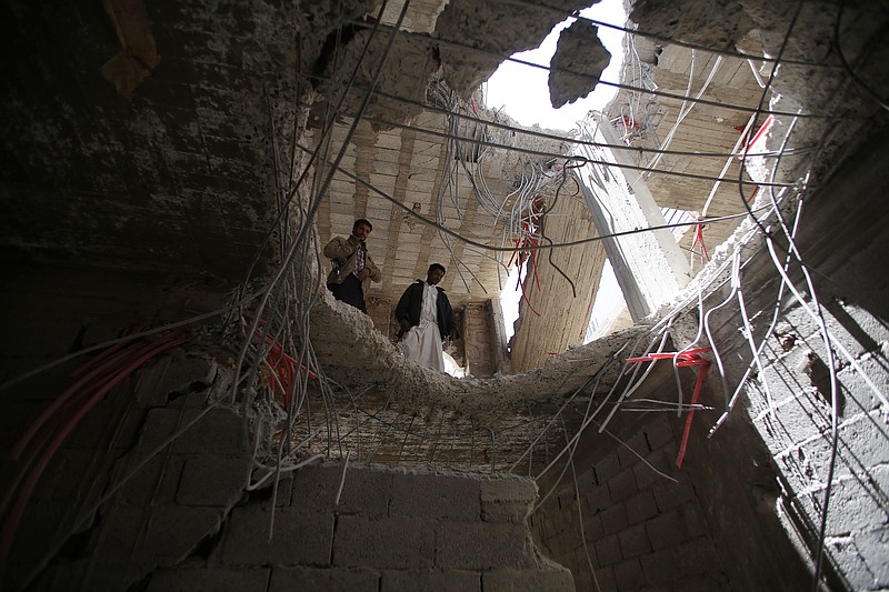 
              Yemeni men look through a hole in a building damaged by a recent Saudi-led airstrike which hit a site which many believe was a large weapons cache in Yemen's capital, Sanaa, Saturday, April 25, 2015.  With combatants fighting in neighborhoods and Saudi-led coalition warplanes pounding Iran-backed rebels from the sky, Yemen's war is wreaking a particularly bloody toll among civilians: more than 550 have been killed in the past month, including 115 children, the U.N. said Friday. (AP Photo/Hani Mohammed)
            