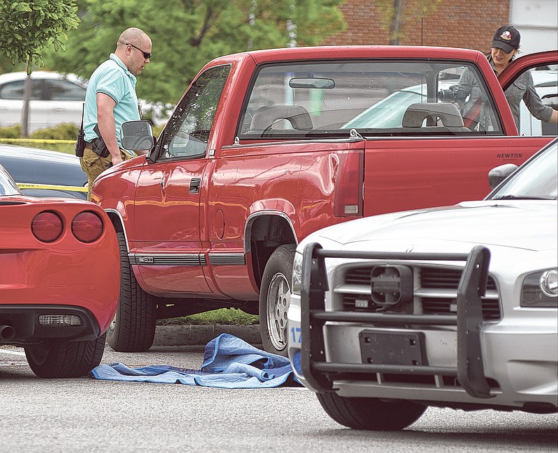 Collegedale detectives Brandon Allen, left, and Kat Cooper investigate the scene of a double shooting that left one person dead in a parking lot of the Ooltewah Crossing shopping center on Sunday in Collegedale. The red pickup truck was the site of the incident.
