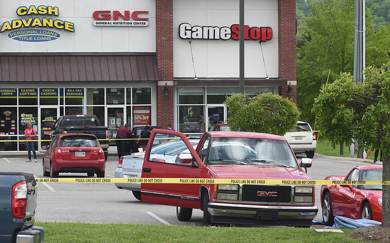 Collegedale police investigate the scene of a double shooting that left one person dead in a parking lot in front of the Game Stop store near Walmart on Sunday, Aug. 26, 2015, in Collegedale, Tenn. The red pickup truck in the foreground was involved in the incident.
