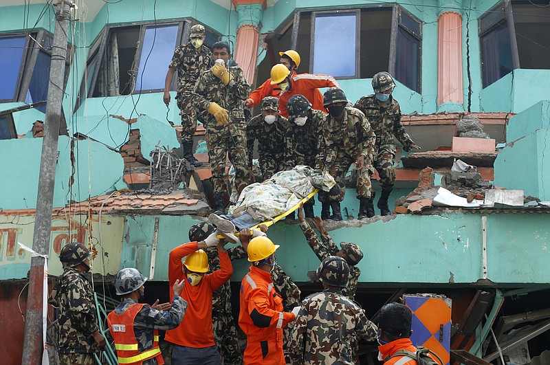 
              In this April 27, 2015 photo, Nepalese and Indian rescue teams remove a body from the collapsed Sitapyla church in Kathmandu, Nepal. A strong earthquake shook Nepal's capital and the densely populated Kathmandu Valley on Saturday. The catastrophe has overwhelmed Nepal’s government, with the challenge expected to worsen as the death toll climbs as rescuers reach vulnerable mountain villages that were hit hard. (AP Photo/Wally Santana)
            
