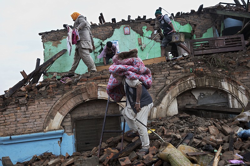 Residents rescue items from debris of a house that was damaged in Saturday's earthquake in Kathmandu, Nepal, Monday, April 27, 2015. 