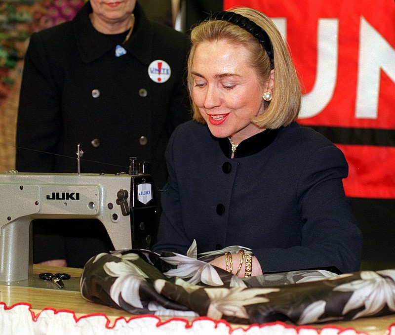 
              FILE - In this March 6, 1996, file photo, then-first lady Hillary Rodham Clinton sews a label into a woman's floral print jacket at designer Nicole Miller's New York showroom as the symbolic first label of UNITE, the organization that resulted from the merger of the International Ladies Garment Workers Union and the Amalgamated Clothing and Textile Workers Union. Clinton’s support for trade deals has fluctuated with the political calendar. As first lady, she trumpeted the North American deal brokered by her husband, telling unionized garment workers in 1996 that the agreement was "proving its worth." Now, early in her Democratic presidential campaign, she’s striking a different tone. (AP Photo/Richard Drew, File)
            