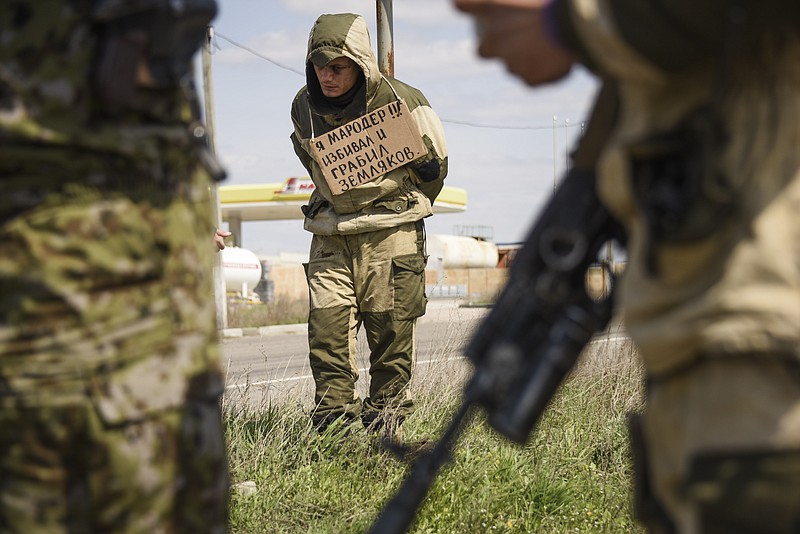 
              A man stands tied to a post by pro-Russian rebels, accused of stealing from local people, with a poster around his neck reading  "I am marauder, I beat and steal from civilians",  standing next to a highway in Krasnyi Partyzan, Ukraine, Thursday, April 23, 2015. (AP Photo/Mstyslav Chernov)
            