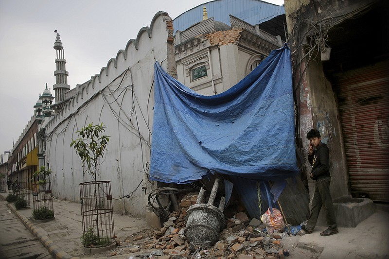 A Nepalese boy talks on a mobile phone near a damaged minaret of a mosque in Kathmandu, Nepal, on Tuesday, April 28, 2015.