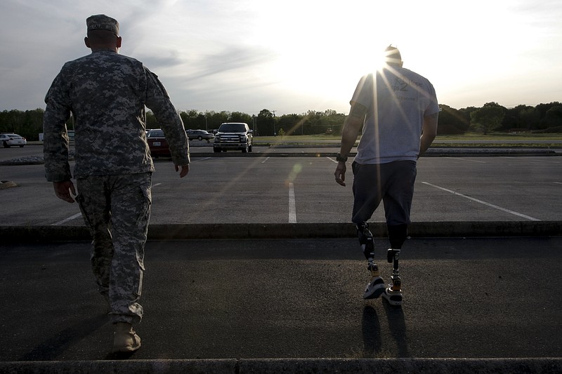 Jason Smith, right, and National Guard Sgt. Andy Calfee walk through the parking lot before a motorcycle parade of veterans and supporters on April 24, 2015, at Camp Jordan in East Ridge, Tenn. Smith lost both of his legs in an IED explosion while serving in the U.S. Army in Afghanistan in 2012. Local volunteers will be building Smith and his wife a new home next week.