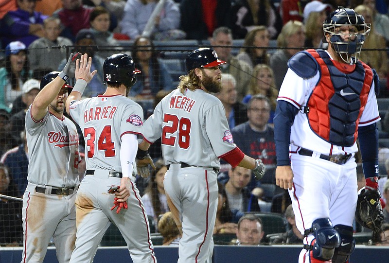 Washington Nationals' Bryce Harper (34) and Jayson Werth (28) are congratulated by teammate Dan Uggla, left, after scoring on on a single by Danny Espinosa as Atlanta Braves catcher A.J. Pierzynski walks away during their game Wednesday, April 29, 2015, in Atlanta. 