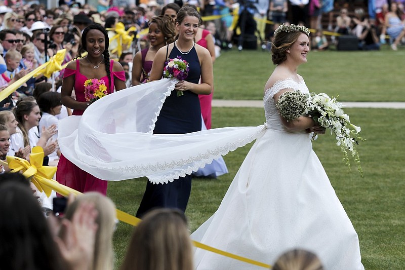 May Queen Mackenzie Hobbs, right, precedes her train bearers, Angela Bonds, left, and Abigail Jansen, as they walk past the crowd during Girls Preparatory School's annual May Day celebration Thursday, April 30, 2015, at the school in Chattanooga, Tenn. 