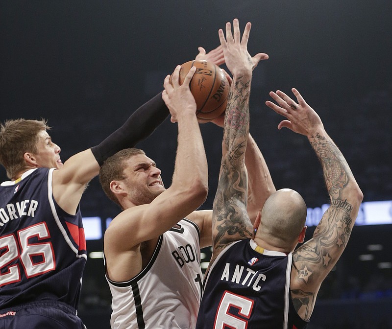 Atlanta Hawks' Kyle Korver (26) and Pero Antic (6) defend Brooklyn Nets' Brook Lopez during their Game 6 in a first round NBA playoff basketball game Friday, May 1, 2015, in New York.