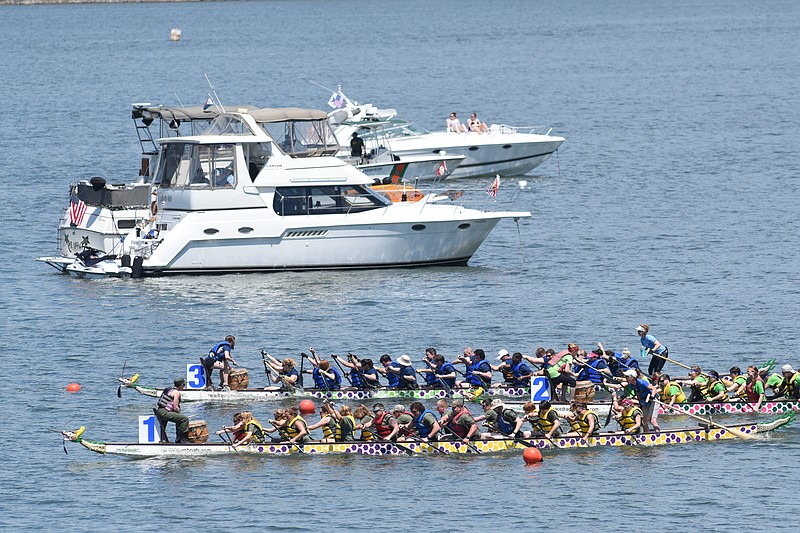 Competitors pass anchored boats during the annual Dragon Boat Races at the Chickamauga Dam beach area Saturday, May 2, 2015. The event benefits the Erlanger Children's Hospital Foundation.