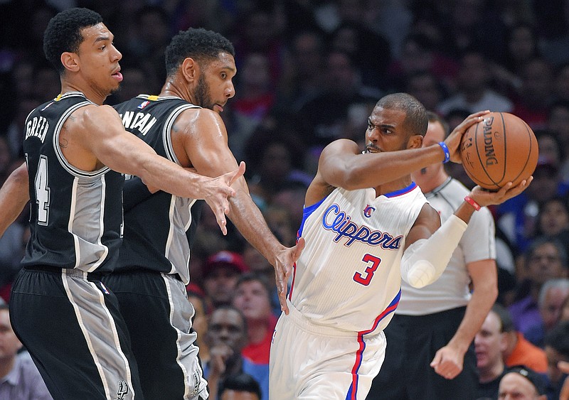 Los Angeles Clippers guard Chris Paul, right, tries to get the ball past San Antonio Spurs guard Danny Green, left, and forward Tim Duncan during their Game 5 of a first-round NBA basketball playoff series, Tuesday, April 28, 2015, in Los Angeles.