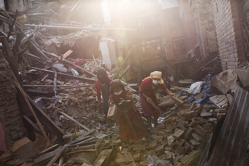 Nepalese woman remove debris searching their belongings from their house that was destroyed a week ago during the earthquake in Bhaktapur, Nepal, Sunday, May 3, 2015.