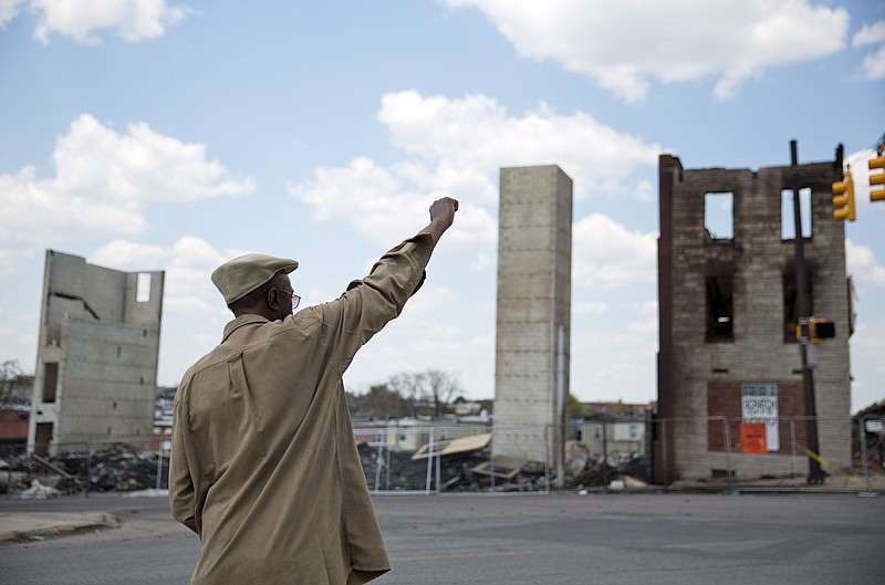 
              James Carter calls out to a friend crossing the street as he stands in front of the remains of a senior center that burned during the riots following Freddie Gray's funeral Sunday, May 3, 2015, in Baltimore. Gov. Larry Hogan has called for a statewide "Day Of Prayer And Peace" on Sunday after civil unrest rocked Baltimore. (AP Photo/David Goldman)
            