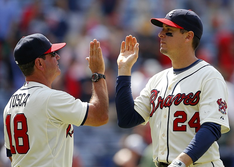 Atlanta Braves' Kelly Johnson (24) celebrates a victory with bench coach Carlos Tosca (18) at the conclusion of a baseball game against the Cincinnati Reds, Sunday, May 3, 2015, in Atlanta. The Braves won the game 5-0. 