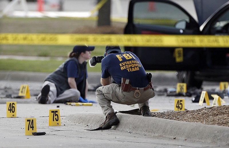 FBI crime scene investigators document the area around two deceased gunmen and their vehicle outside the Curtis Culwell Center in Garland, Texas, on Monday, May 4, 2015. 