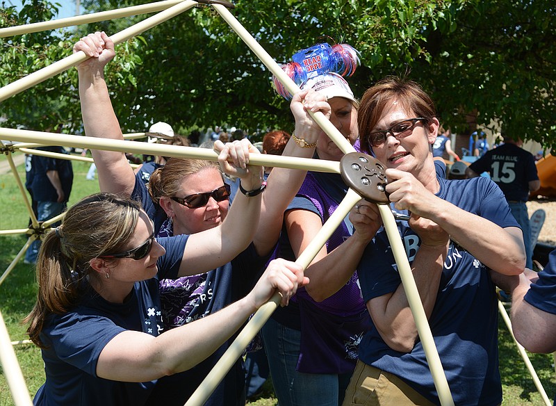 Julie Conyer, Angela Wheeler, Janet Brown and Dawn Weber, from left, assemble equipment as they and more than 200 other volunteers build a new playground at Hope for the Inner City on Roanoke Avenue on Tuesday.