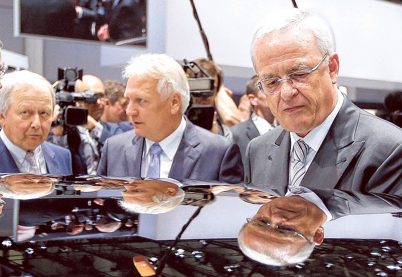 Volkswagen CEO Martin Winterkorn, Skoda CEO Winfried Vahland and Wolfgang Porsche, members of the supervisory board, from right, are reflected on the roof of a car during a tour around a fair hall before the annual shareholder meeting of the car manufacturer Volkswagen in Hanover, Germany, on Tuesday.