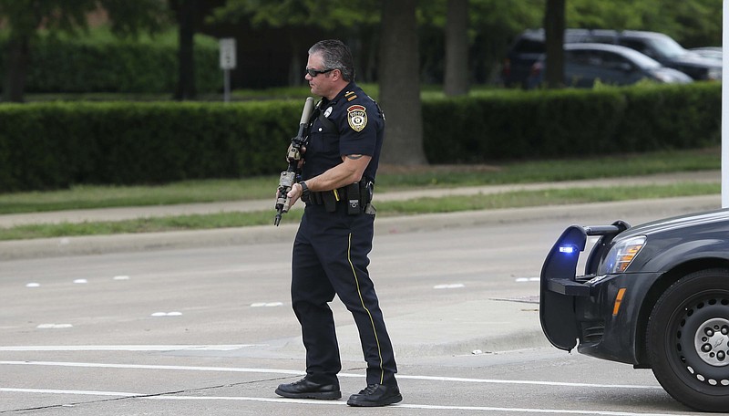 A Garland Police Officer stands guard at the road leading to Naaman Forest High School and Curtis Culwell Center after a fire alarm was called at the high school, Tuesday, May 5, 2015, in Garland, Texas. A man whose social media presence was being scrutinized by federal authorities was one of two suspects in the Sunday shooting at this location that hosted a cartoon contest featuring images of the Muslim Prophet Muhammad. The Islamic State group claimed responsibility for the attack.