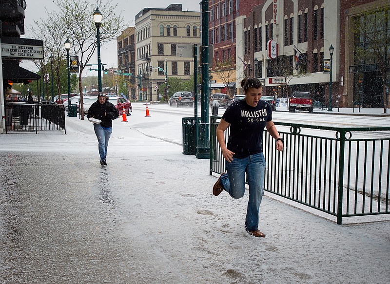 Pedestrians run through the hail in downtown Colorado Springs, Colo., on Saturday, May 9, 2015, as another storm hits El Paso County.