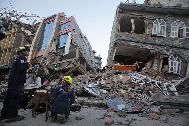 USAID rescue workers inspect the site of collapsed buildings after an earthquake in Kathmandu, Nepal, Tuesday, May 12, 2015. A new earthquake Tuesday spread more fear and misery in Nepal, which is still struggling to recover from a devastating quake nearly three weeks ago that left thousands dead. (AP Photo/Bikram Rai)