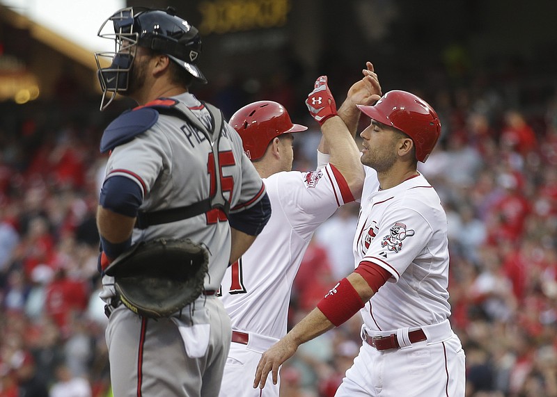 Cincinnati Reds' Todd Frazier, center, celebrates with teammate Joey Votto, right, after hitting a two-run home run as Atlanta Braves catcher A.J. Pierzynski stands at home plate in the first inning of a baseball game, Tuesday, May 12, 2015, in Cincinnati.