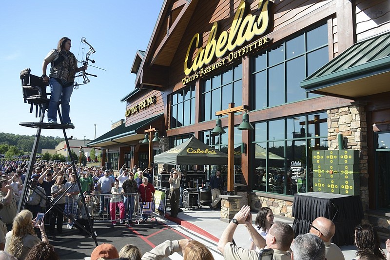 Cabela employee Tiffany Westbrook prepares to cut the ribbon at the grand opening of the new Cabela store Wednesday, May 13,  2015, in Fort Oglethorpe, Ga. Westbrook climbed a deer stand and used a compound bow to shoot an arrow into a target and break the ribbon.