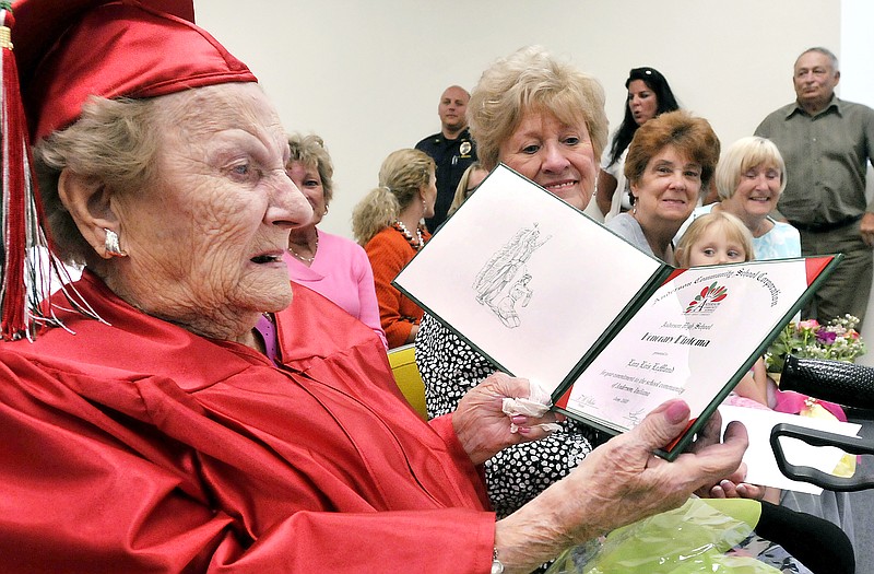 
              Wearing her cap & gown Lora Lois LeMond White Hardy, 99, looks over the honorary diploma from Anderson High School in Anderson, Ind. she received Tuesday May 12, 2015 from the Anderson Community Schools board of trustees.  Lora, who turns 100 on May 28, had to quit school her senior year in 1933 just four credits shy of her diploma to go to work to help support her family. (AP Photo/The Herald Bulletin, John P. Cleary)
            
