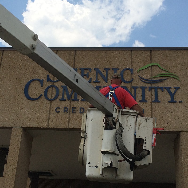 A worker changes the name of Dupont Community Credit Union to Scenic Community Credit Union.
