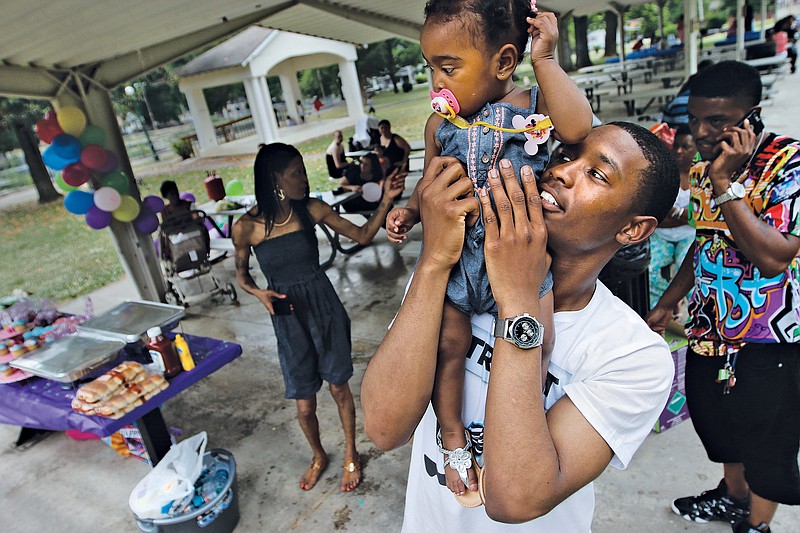 Jamaine Akins holds his niece Journee Akins on his shoulder during Journee's first birthday party at East Lake Park in Chattanooga on  Saturday, May 16, 2015. Journee's mother, Jasmine Akins, was shot and killed last year, when Journee was just 4 months old.
