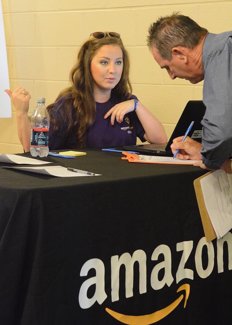 Hannah Fricke directs Ken Dunlevy, right, as he enrolls at an Amazon job fair in this file photo.