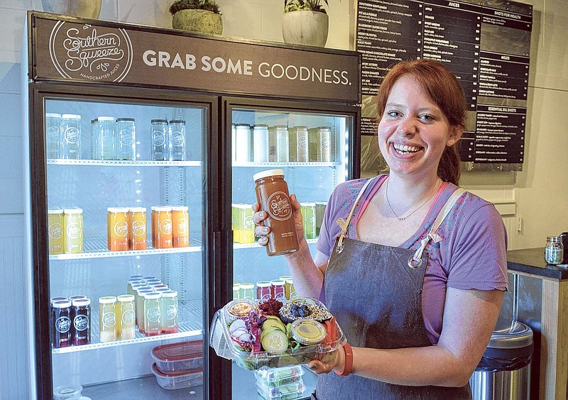 Southern Sqweeze employee Anna Stroud holds a salad and a handmade, cold-pressed, organic fruit drink at the company's location in Miller Plaza on Wednesday, May 20, 2015.