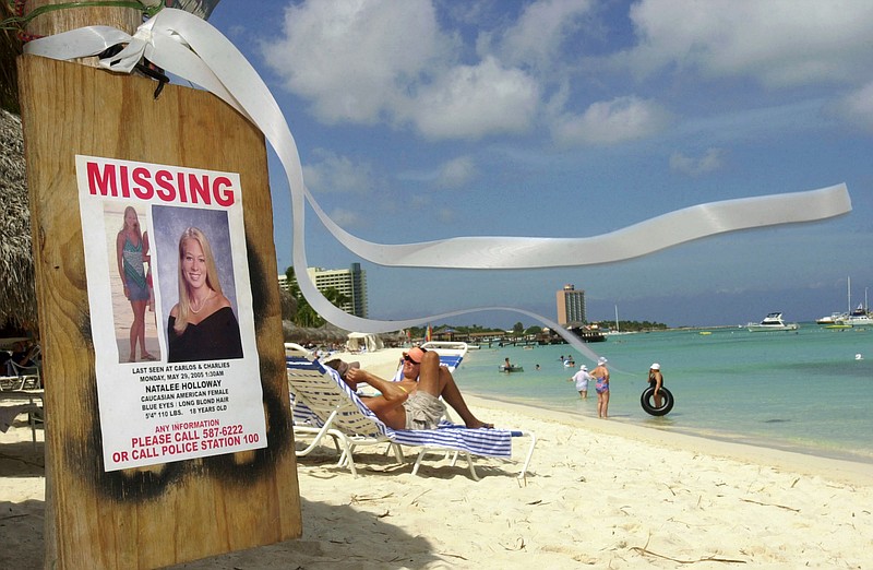 This June 10, 2005, file photo shows a missing poster for Natalee Holloway, a high school graduate of Mountain Brook, Ala., who disappeared while on a graduation trip to Aruba on May 30, 2005, on Palm Beach where tourists sunbathe in Aruba.