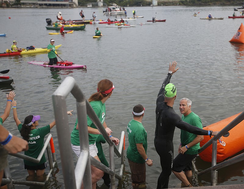 An athlete waves from Ross's Landing to volunteers on paddle boards and kayaks in the Tennessee River who helped him during the swim portion Ironman Triathlon in Chattanooga on Sept. 28, 2014.