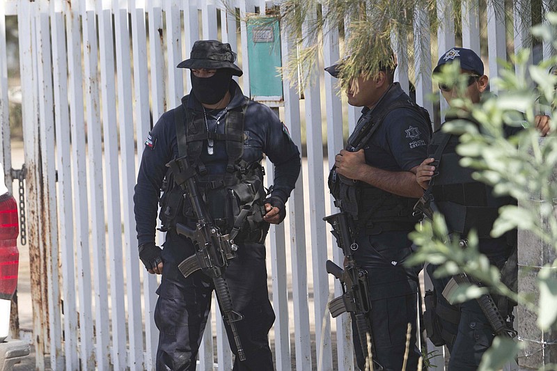 
              Mexican state police stand guard near the entrance of Rancho del Sol, near Vista Hermosa, Mexico, Friday, May 22, 2015. About 40 people were killed Friday in what authorities described as a large-scale shootout between law enforcement and criminal suspects. Almost all the dead were suspected criminals, said a Federal Police official. The confrontation, which occurred near the border of Michoacan and Jalisco states, started when federal police officers tried to pull over a truck on the highway near the ranch. (AP Photo/Refugio Ruiz)
            