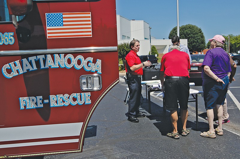 Interim Fire Chief Chris Adams, left, talks with the public before a meeting Saturday in the parking lot of Redemption Point Church in Chattanooga to discuss the construction of a new Fire Station No. 5. Some residents are concerned about the change, which would include a switch from two old firetrucks to a single new truck.