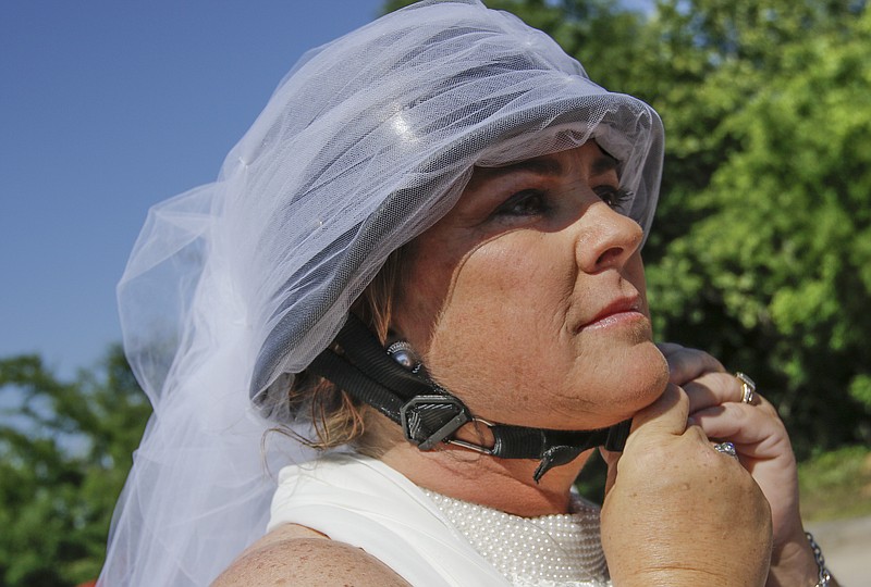 Tracy Bialczak straps on a helmet outfitted with a veil before her wedding by motorcycle to Greg Abbott on Saturday, May 23, 2015, in Soddy-Daisy. Bialczak and Abbot exchanged rings while traveling on motorcycles along U.S. Highway 27 southbound before completing their wedding ceremony at Charlie's Lounge.