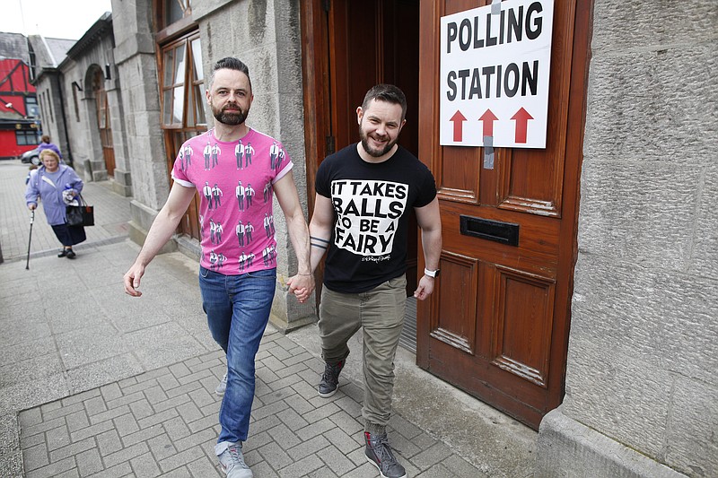 
              Partners Adrian, centre left and Shane, leave a polling station after casting their vote in Drogheda, Ireland, Friday, May 22, 2015.  Ireland began voting Friday in a referendum on Gay marriage which will require an amendment to the Irish constitution. Opinion polls throughout the two-month campaign suggest the government-backed amendment should be approved by the required majority of voters when results are announced Saturday.  (AP Photo/Peter Morrison)
            