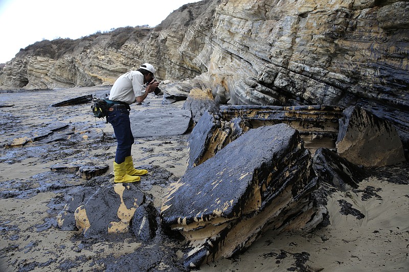 David Ledig, a national monument manager from the Bureau of Land Management, takes pictures of rocks covered in oil at Refugio State Beach, north of Goleta, Calif., on May 21, 2015. 