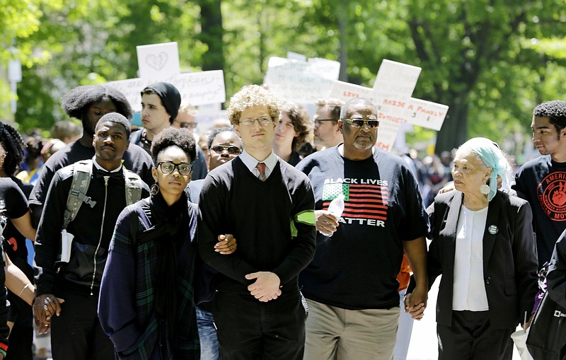 Protesters link arms and hands as they walk near where the county prosecutor lives in Cleveland, Ohio, on Saturday, May 23, 2015. 