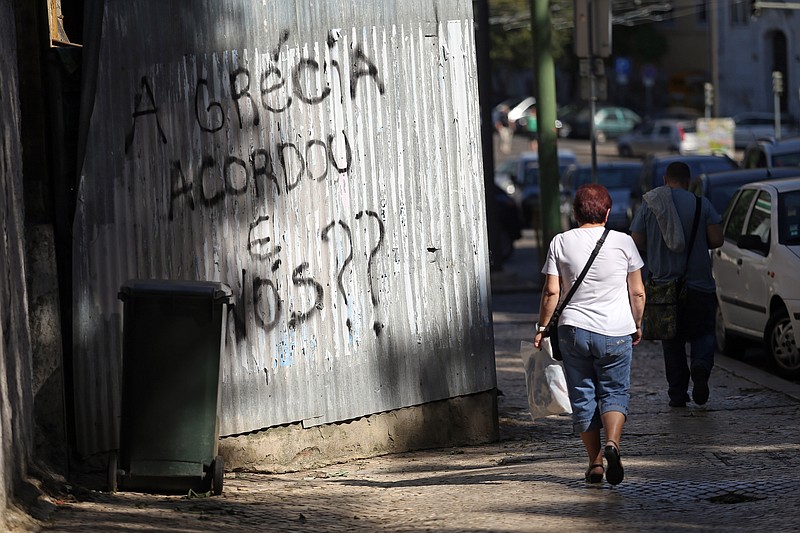 
              People walk past a graffiti that reads in Portuguese: "Greece woke up, what about us?" in Lisbon, Thursday, May 21, 2015. European Central Bank head Mario Draghi said that "growth is too low everywhere" in Europe despite a modest recovery, during an ECB's conference on inflation and unemployment in Sintra, Portugal. (AP Photo/Francisco Seco)
            