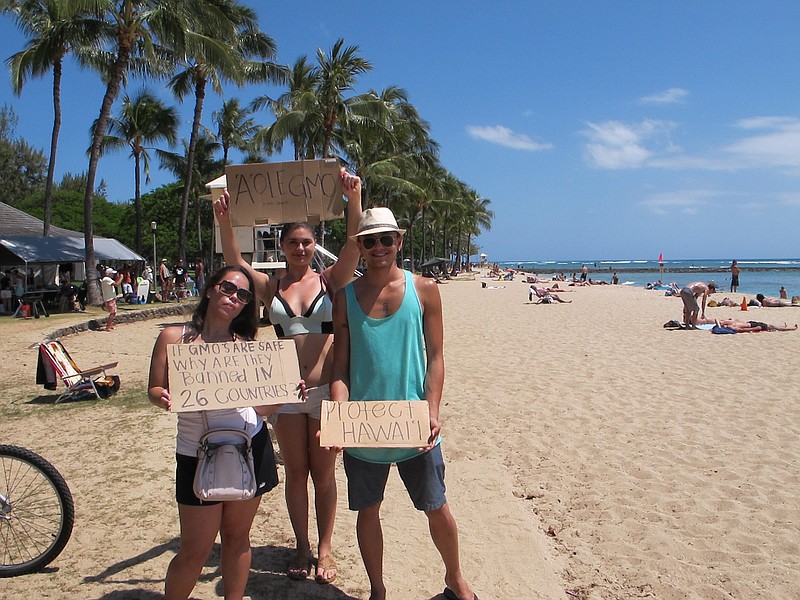 
              Pohai George, left, Ashley Montogmery and Nathaniel Whittaker, right, protested against Monsanto at a Waikiki Beach rally in Honolulu on Saturday, May 23, 2015. They were part of an international day of protests against the company. (AP Photo/Cathy Bussewitz)
            