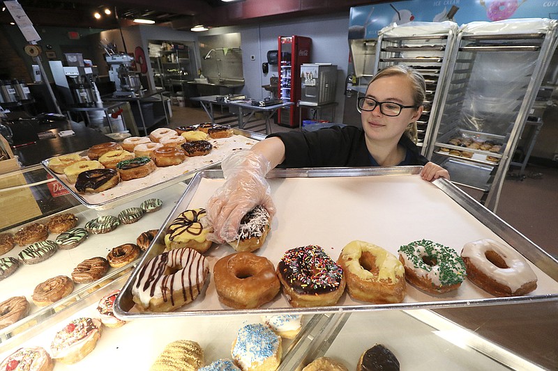 Molly Hall puts a selection of hand-decorated doughnuts in the case at Julie Darling Donuts on Frazier Avenue.