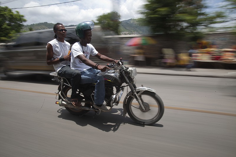 
              In this May 21, 2015 photo, Joseph Marc Carel, a motorcycle taxi driver, takes a passenger to downtown Port-au-Prince, Haiti. Carel knows the danger of ferrying passengers on his small motorbike, sometimes two at a time, as tides of the buzzing vehicles cut through the chaotic Haitian capital. He has a prosthetic leg to prove it. (AP Photo/Dieu Nalio Chery)
            