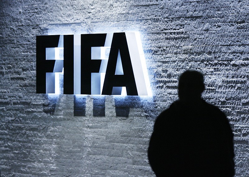 
              FILE - In this Oct. 29, 2007 file photo, a person stands next to the FIFA logo at the FIFA headquarter in Zurich, Switzerland. The Swiss Federal Office of Justice said six soccer officials have been arrested and detained pending extradition at  the request of U.S. authorities ahead of the FIFA congress in Zurich. In a statement Wednesday, May 27, 2015, the FOJ said U.S. authorities suspect the officials of having received paid bribes totaling millions of dollars.  (Steffen Schmidt/Keystone via AP, File)
            