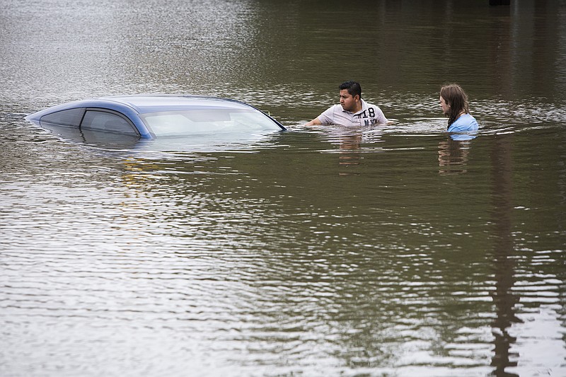 Roberto Salas, left, and Lewis Sternhagen check a flooded car on the frontage road between South Loop West Freeway and South Post Oak Road near the Willow Waterhole Bayou, Tuesday, May 26, 2015, in Houston.
