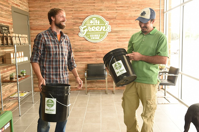 Green's Eco Build & Design owners Sam Young, left, and Tyler Smith hold recycled plastic buckets in the showroom of the new business on Riverside Drive.