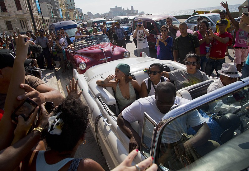 
              Fans take photographs of pop artist Rihanna, center,  as she rides on an American classic car after a photo shoot with photographer Annie Leibovitz at a building on the Malecon, in Havana, Cuba, Friday, May 29, 2015. (AP Photo/Desmond Boylan)
            
