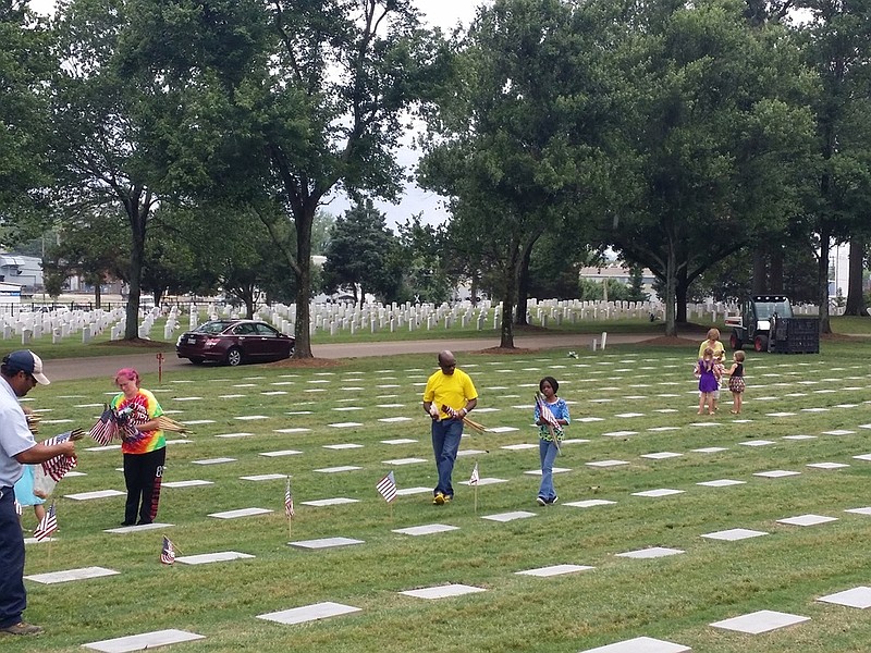 Volunteers pick up and secure U.S. flags at the Chattanooga National Cemetery. The cemetery received volunteers of all ages throughout two days starting Tuesday morning.