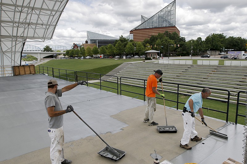 Joseph Johnson, Eric Brown and Eddie Dial, from left, paint the floor of the Coca-Cola Stage on Thursday while preparing for the start of the Riverbend Festival at Ross's Landing. The festival begins Friday.