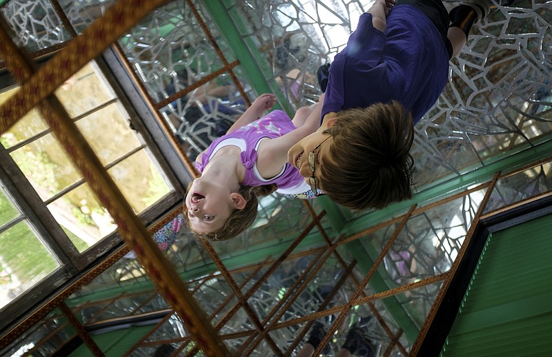 Ella Weaver, left, and her brother Noah look upwards inside of a mirror room Saturday, May 30, 2015, at Paradise Garden during Finster Fest in Summerville, Ga. The annual folk art festival, named for native artist Howard Finster, includes music and displays of local art.